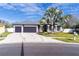 Charming gray home featuring a well manicured lawn, a three-car garage, and beautiful palm tree at 28752 Falling Leaves Way, Wesley Chapel, FL 33543