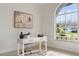 Home office features a work desk, neutral decor, and natural light from the large arched window at 28752 Falling Leaves Way, Wesley Chapel, FL 33543