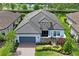 Beautiful aerial view of a home with lush landscaping, a lake view, and a gray tiled roof at 3130 Forsythia Dr, Odessa, FL 33556
