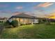 Backyard view showcasing the lush lawn, patio, and meticulously maintained landscaping with an evening sky at 3130 Forsythia Dr, Odessa, FL 33556