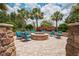 Community fire pit with stone surround, lush landscaping and comfortable seating, perfect for outdoor relaxation at 3130 Forsythia Dr, Odessa, FL 33556