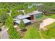 Aerial view of modern home with unique architecture, stylish exterior, deck, waterfront, and lush landscaping at 3130 Forsythia Dr, Odessa, FL 33556