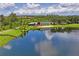 Scenic aerial view of lake with a community building, surrounded by lush trees and a walking path at 3130 Forsythia Dr, Odessa, FL 33556