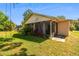 View of the house's backyard with an exterior porch, vibrant plants, and a tree swing at 3273 Bluestone Ave, Spring Hill, FL 34609