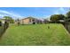 Spacious, fenced backyard showcasing the home's exterior and screened-in pool area at 3542 Conifer Loop, Spring Hill, FL 34609