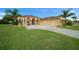 Beautiful tan home with a well-manicured lawn, palm trees, and an attached three-car garage at 3542 Conifer Loop, Spring Hill, FL 34609