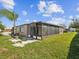 An outdoor view of the home's backyard and screened-in patio, with lush grass and mature trees at 3730 Sail Dr, New Port Richey, FL 34652