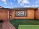 Close-up of home exterior featuring a faux grass yard, tiled walkway, and a window with security bars at 3730 Sail Dr, New Port Richey, FL 34652