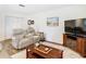 Cozy living room featuring wood floors, a beige sofa, and a dark wood coffee table at 5434 Glover Dr, Weeki Wachee, FL 34607