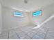 Bright bedroom featuring tile floors, dual windows, and a neutral color palette at 7421 San Miguel Dr, Port Richey, FL 34668