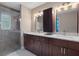 Elegant bathroom featuring double sinks, granite countertops, dark wood cabinets and walk-in shower at 7485 Sugarbush Dr, Spring Hill, FL 34606