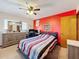 Bedroom with colorful striped bedding, a desk setup, and a bright red accent wall at 8173 Wysocki Ct, Spring Hill, FL 34606