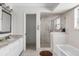 Bright bathroom with a marble vanity, glass-enclosed shower, and soaking tub at 8408 Damen Ln, Port Richey, FL 34668
