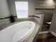 Close-up of soaking tub and shower featuring decorative tiling and natural light at 9089 Dupont Ave, Spring Hill, FL 34608