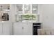 Wet bar area with white cabinets, wine fridge, and large window overlooking greenery at 9851 Domingo Dr, Brooksville, FL 34601