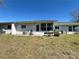 The backyard view showcases the exterior of the home with its lawn and sliding glass door to sunroom at 12205 Darwood Dr # 12205, Hudson, FL 34667