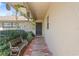 Inviting covered front porch with brick pavers, complemented by hanging plants, greenery, and a cozy bench at 12279 Penfield St, Spring Hill, FL 34609