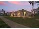 A single-story home with manicured lawn and palm trees at twilight at 14251 Mansfield Rd, Spring Hill, FL 34609