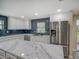 Bright kitchen featuring white cabinets, stainless steel appliances, and a marble countertop island with a blue tile backsplash at 14821 Sassandra Dr, Odessa, FL 33556
