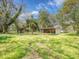 Wide shot of property showing green grass, open barn, metal shed, and storage shed at 14821 Sassandra Dr, Odessa, FL 33556