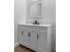 Bathroom vanity with gray cabinets, dark hardware and framed mirror at 15188 Riverside Ln, Nobleton, FL 34661