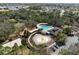 Aerial view of a community pool with a playground and splash pad surrounded by trees at 3667 Autumn Amber Dr, Spring Hill, FL 34609