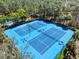 Aerial shot showcasing well-maintained blue tennis courts surrounded by lush greenery at 3667 Autumn Amber Dr, Spring Hill, FL 34609