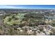 Wide aerial view of a community with homes, lush green golf course, mature trees, and beautiful lakes at 3806 River Oaks Ct, New Port Richey, FL 34655