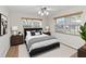 Bright bedroom features a ceiling fan, two windows with blinds, wood-look flooring, and a black upholstered bed at 3806 River Oaks Ct, New Port Richey, FL 34655