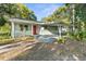Charming single-story home with a bright red front door and covered carport, set amidst lush greenery at 406 Zoller St, Brooksville, FL 34601