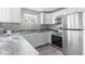 Well-lit kitchen boasts white cabinets, stainless steel appliances, and grey stone-look countertops at 406 Zoller St, Brooksville, FL 34601