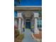 An inviting entrance with a blue double door, columns, and potted yellow flowers at 494 Village Dr, Tarpon Springs, FL 34689