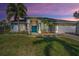 Charming single-story home featuring a beautiful teal door, well-manicured lawn, and lush landscaping at 494 Village Dr, Tarpon Springs, FL 34689