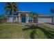 Charming single-story home featuring a beautiful teal door, well-manicured lawn, and lush landscaping at 494 Village Dr, Tarpon Springs, FL 34689