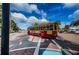 A bright yellow and red trolley in a street view, under a clear, partly cloudy, blue sky at 494 Village Dr, Tarpon Springs, FL 34689