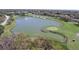 An aerial view of a scenic golf course pond with a fountain and surrounding lush greenery at 7106 Green Abbey Way, Spring Hill, FL 34606