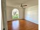 Bright bedroom featuring hardwood floors, a ceiling fan, and a decorative arch window at 7106 Green Abbey Way, Spring Hill, FL 34606