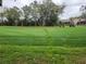 Expansive golf course view with lush green grass, mature trees, and golf carts on the path leading to a nearby home at 7106 Green Abbey Way, Spring Hill, FL 34606