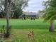 Scenic golf course view featuring two golf carts on lush green grass with mature trees and a screened-in porch in the background at 7106 Green Abbey Way, Spring Hill, FL 34606