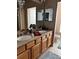 Bathroom featuring double sinks, vanity with wood cabinets, and large mirror at 8337 Shallow Creek Ct, New Port Richey, FL 34653