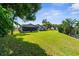 Large grassy backyard featuring mature trees and view of rear exterior at 8721 Latham Dr, Hudson, FL 34667