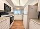 Well-lit kitchen features white cabinets, granite counters, and wood-look flooring at 9512 Sunshine Blvd, New Port Richey, FL 34654