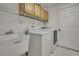 Laundry room with utility sink, washer, dryer, overhead cabinets, and a door to the exterior at 11257 Frigate Bird Ave, Weeki Wachee, FL 34613