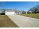 A light blue home offers an attached garage and bay window, with a long driveway and green lawn at 11358 Linden Dr, Spring Hill, FL 34608