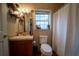 Well-lit bathroom featuring a window, vanity with decorative shelves and a white shower curtain at 13024 Mohican Ave, New Port Richey, FL 34654
