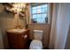 Charming bathroom with a sink vanity, toilet, window, and open shelving for a practical design at 13024 Mohican Ave, New Port Richey, FL 34654