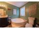 Bathroom featuring a soaking tub, green walls, and natural light at 13024 Mohican Ave, New Port Richey, FL 34654