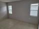 This is an empty bedroom with tile flooring, light gray walls and two windows at 2628 Wildwood Ln, Palm Harbor, FL 34684