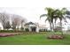 The exterior of a well-maintained clubhouse, featuring manicured lawns, flower beds and tall palm trees at 2641 Royal Ridge Dr, Spring Hill, FL 34606