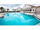 Resort-style community pool with expansive deck, blue umbrellas, palm trees and clubhouse for resident's enjoyment at 2641 Royal Ridge Dr, Spring Hill, FL 34606